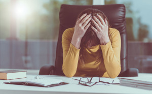 Desperate businesswoman with head in hands, light effect